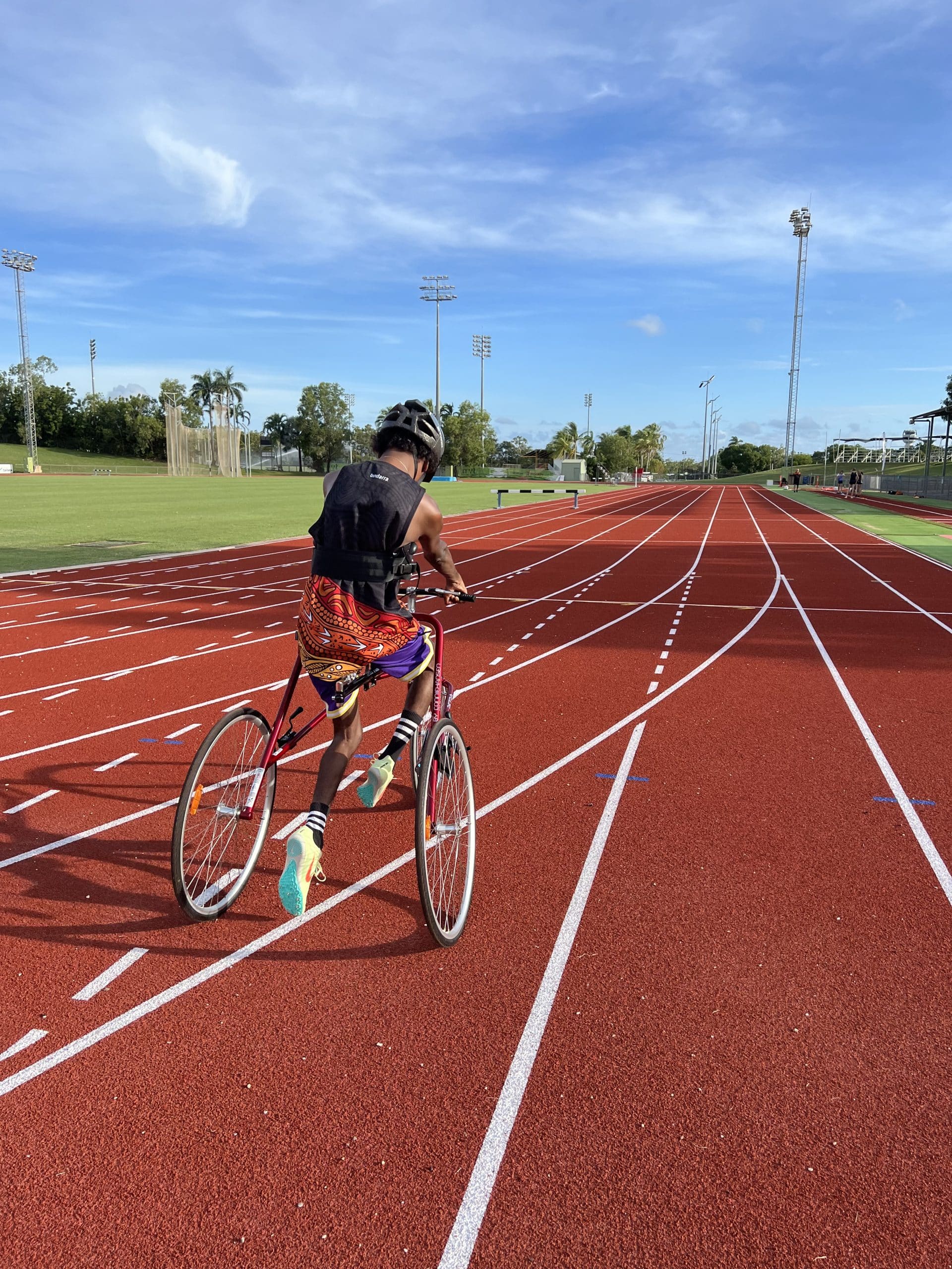 Participant riding an adaptive bike on an athletics track in Darwin