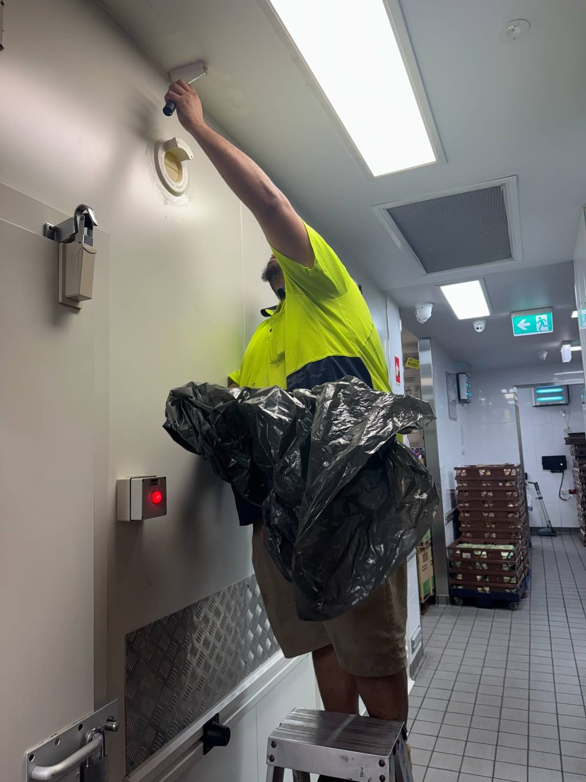Participant cleaning a vent in a commercial kitchen during supported work