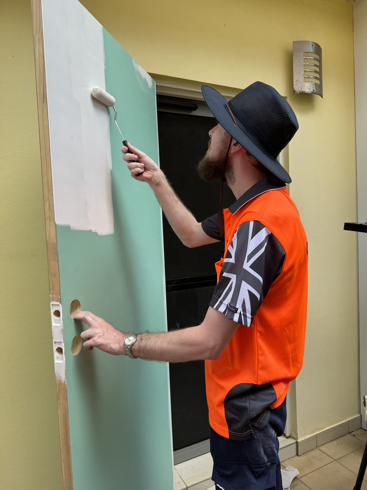 Participant painting a door with a roller during a supported work shift