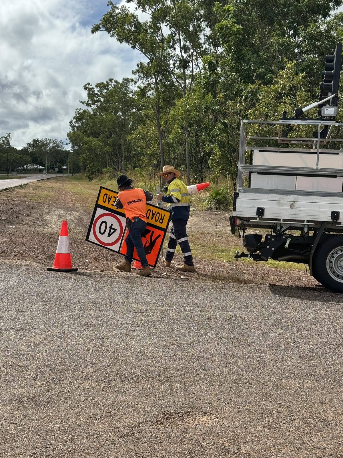Participant holding a slow/stop sign at a roadside job near a work ute